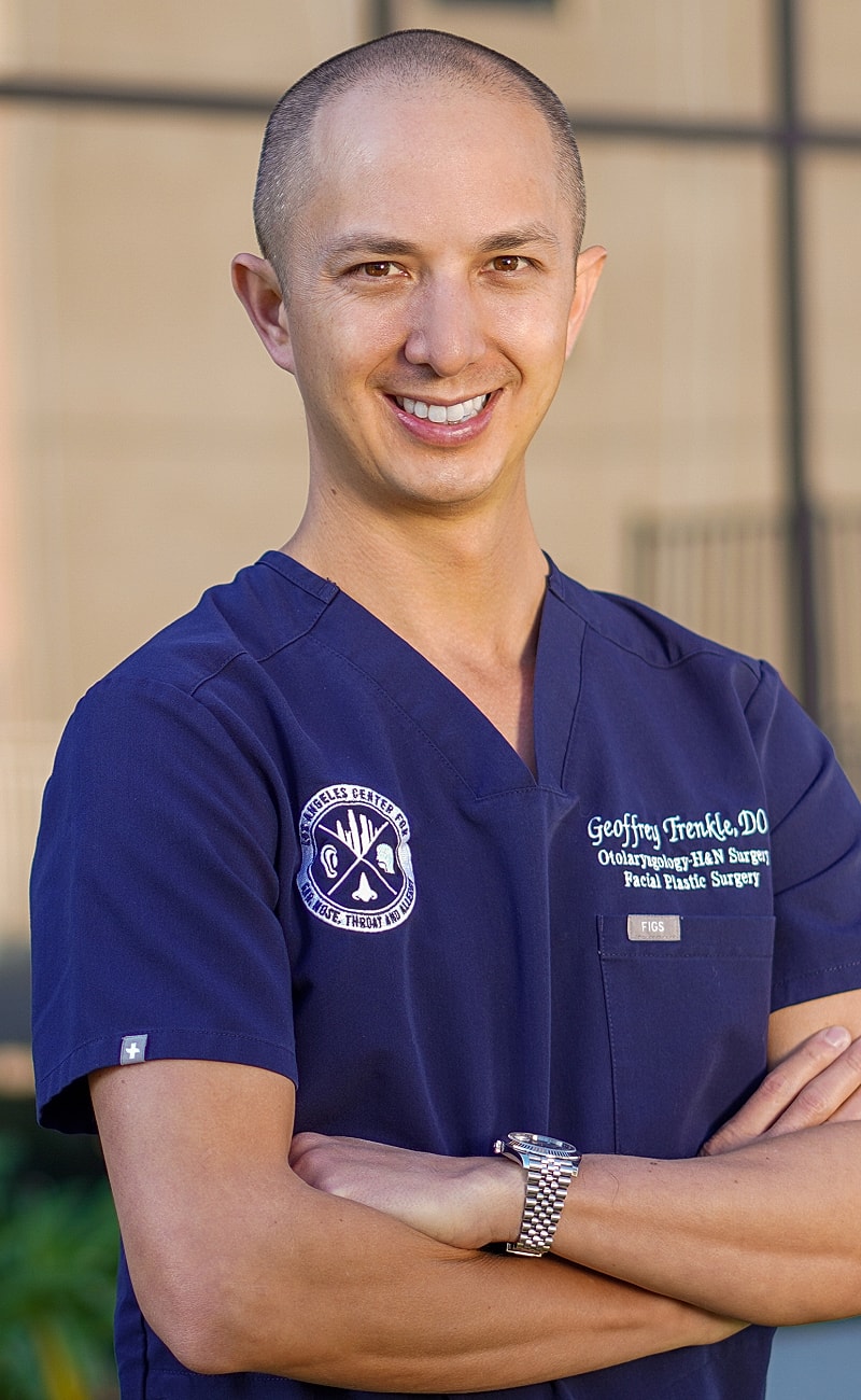 Otolaryngologist in medical scrubs, smiling confidently.