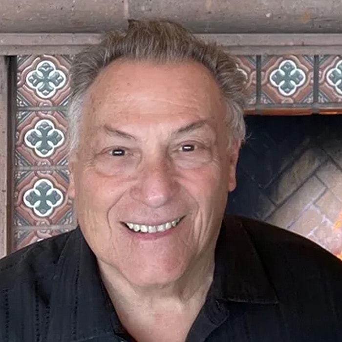 Smiling man in front of a decorative fireplace.