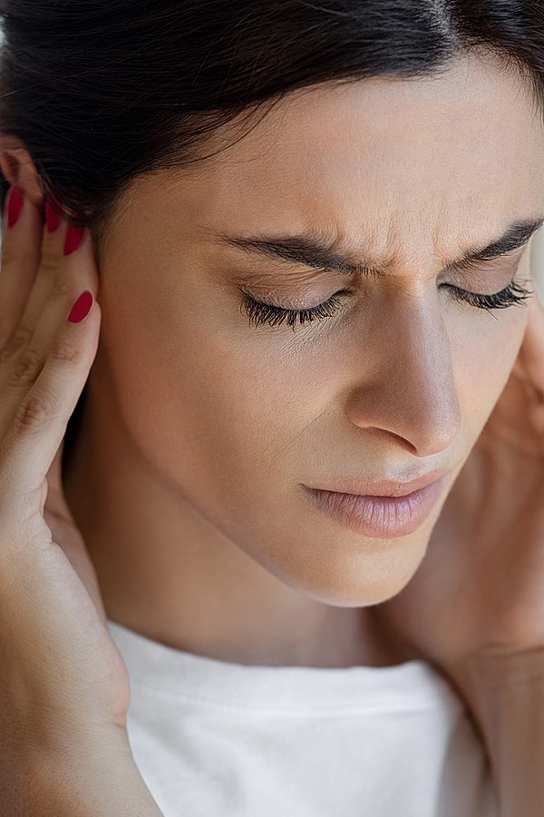 Woman experiencing pain holding her head.