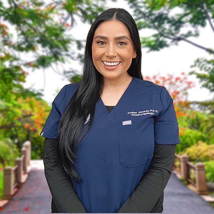 Smiling healthcare professional in scrubs outdoors.
