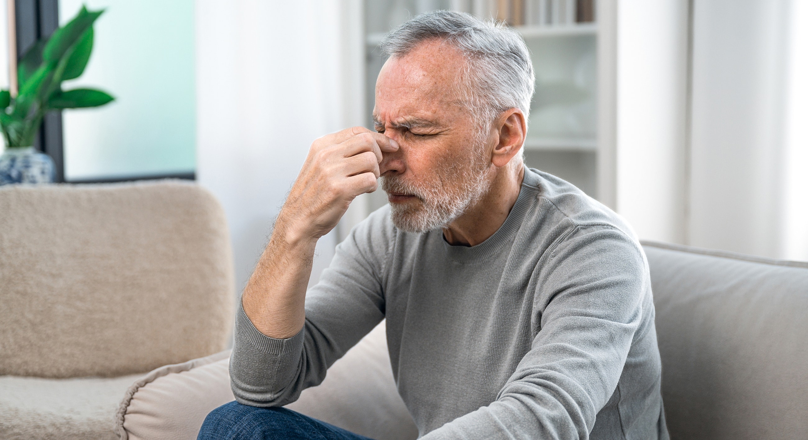 Man expressing discomfort while sitting indoors.