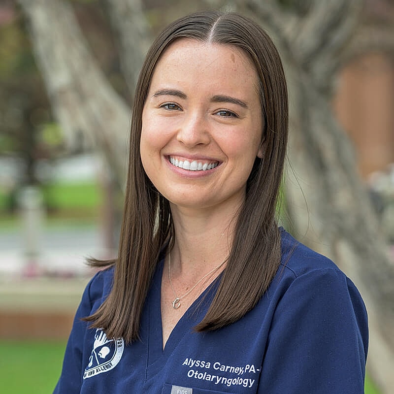 Healthcare professional smiling outdoors, wearing scrubs