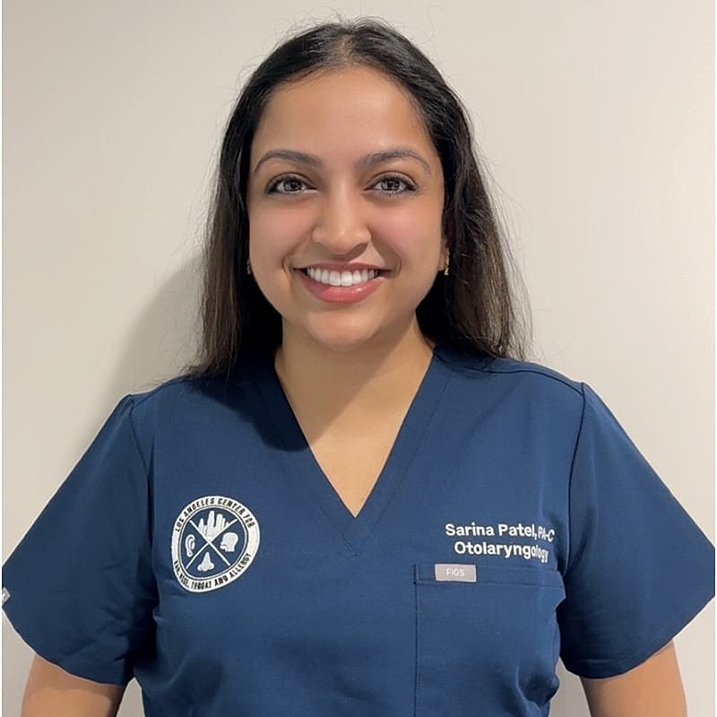 Healthcare professional in blue scrubs smiling.