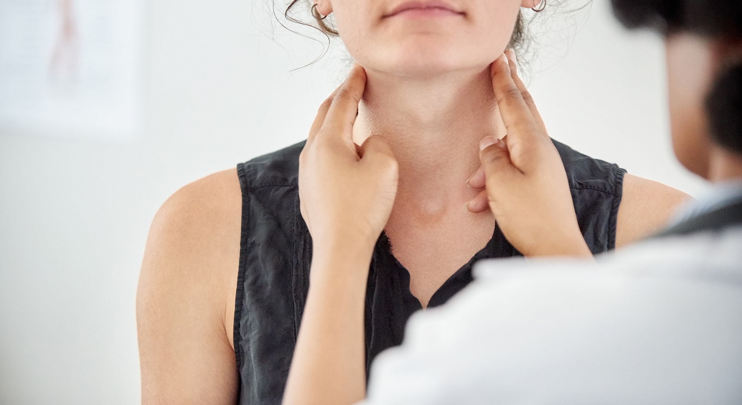 Health professional examining patient's neck area.